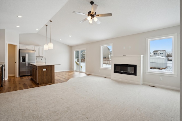 carpeted living room featuring ceiling fan, lofted ceiling, and sink