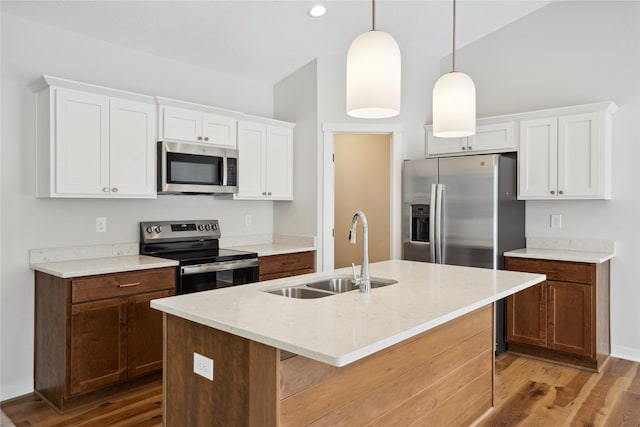 kitchen featuring sink, an island with sink, pendant lighting, white cabinets, and appliances with stainless steel finishes