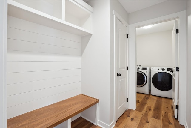 clothes washing area with washing machine and dryer and hardwood / wood-style flooring