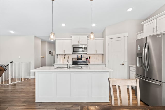 kitchen featuring decorative backsplash, stainless steel appliances, sink, pendant lighting, and white cabinets