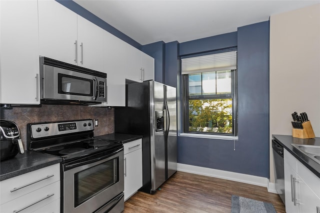 kitchen featuring dark countertops, appliances with stainless steel finishes, decorative backsplash, and dark wood-type flooring