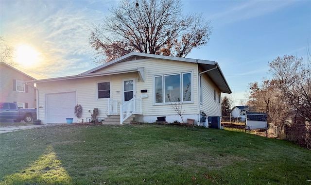 view of front of house featuring a lawn, a garage, and central AC