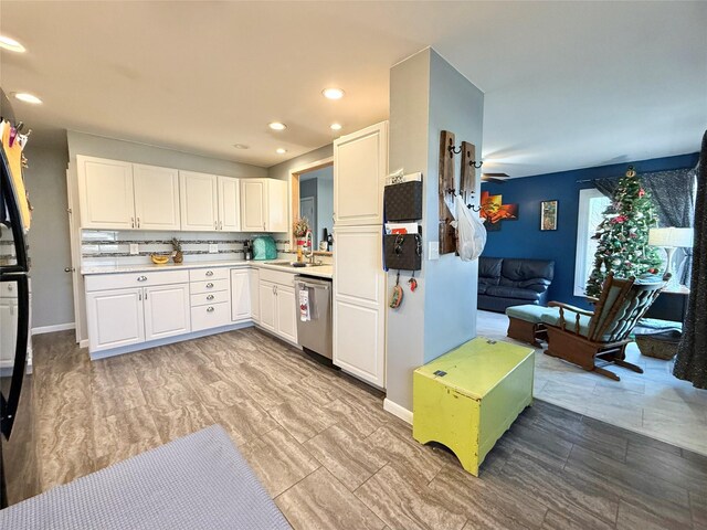 kitchen with stainless steel dishwasher, decorative backsplash, and white cabinetry