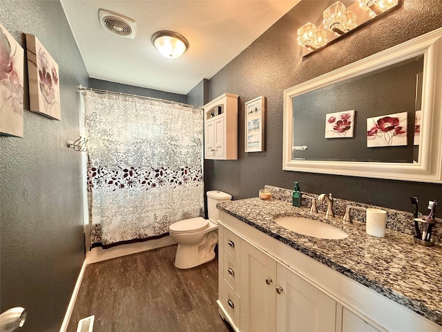 bathroom with walk in shower, hardwood / wood-style floors, a textured ceiling, toilet, and vanity