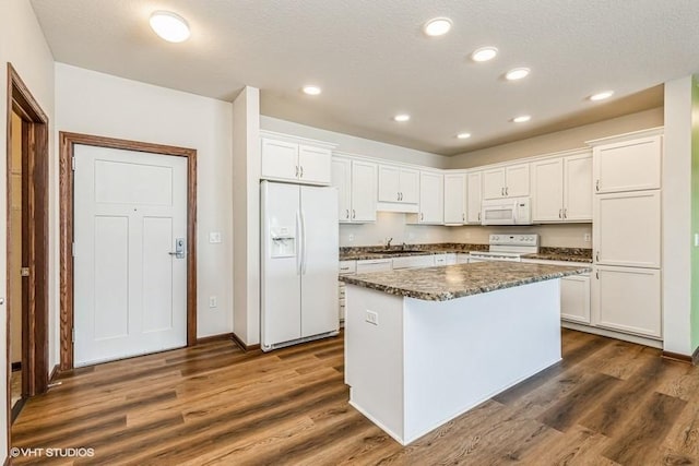 kitchen featuring white cabinets, a center island, and white appliances