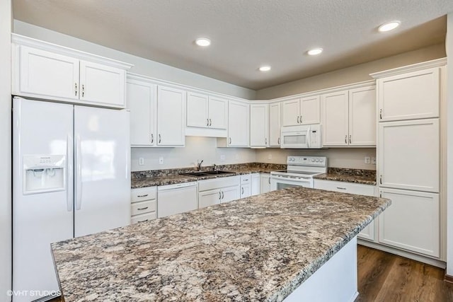 kitchen featuring white appliances, white cabinetry, dark stone counters, and sink