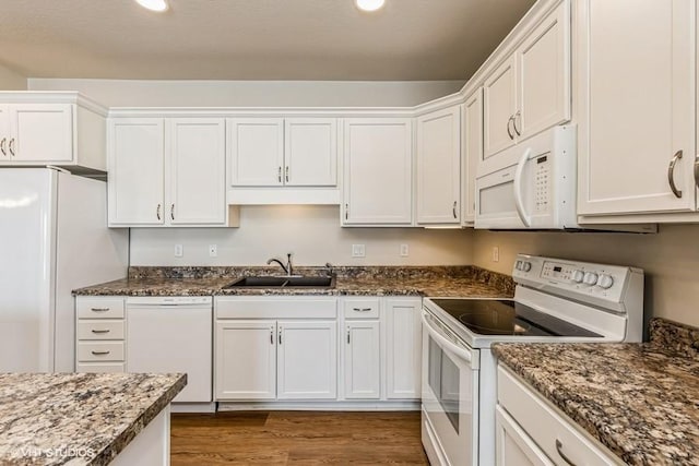 kitchen with dark stone counters, white appliances, dark wood-type flooring, sink, and white cabinetry