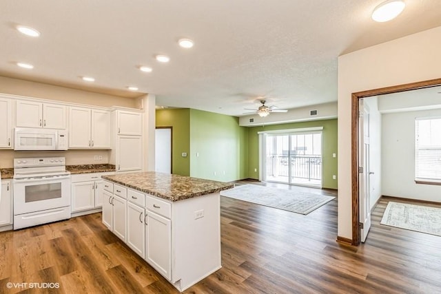 kitchen featuring a center island, white appliances, dark stone counters, a wealth of natural light, and white cabinetry