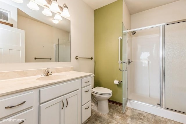 bathroom with vanity, a shower with shower door, and toilet