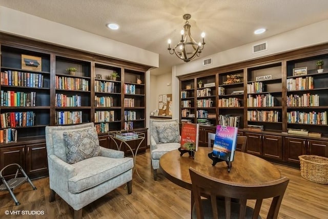 sitting room with light hardwood / wood-style floors, a textured ceiling, and an inviting chandelier