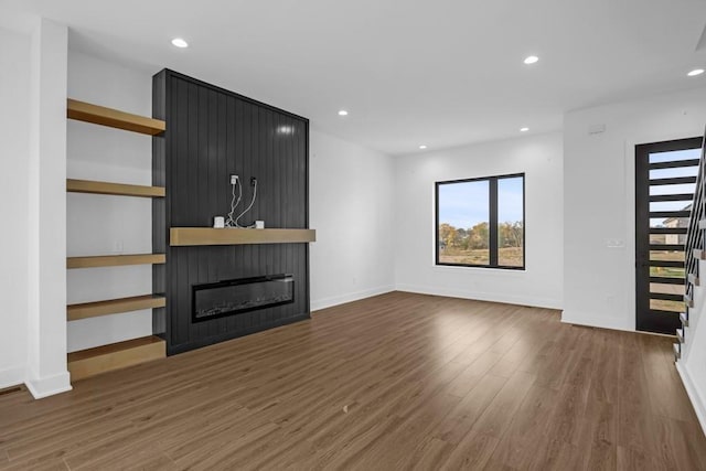 unfurnished living room featuring a large fireplace and dark hardwood / wood-style floors