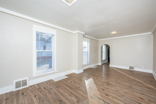 empty room with wood-type flooring and crown molding