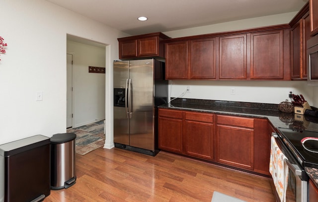 kitchen with dark stone counters, stainless steel appliances, and light wood-type flooring