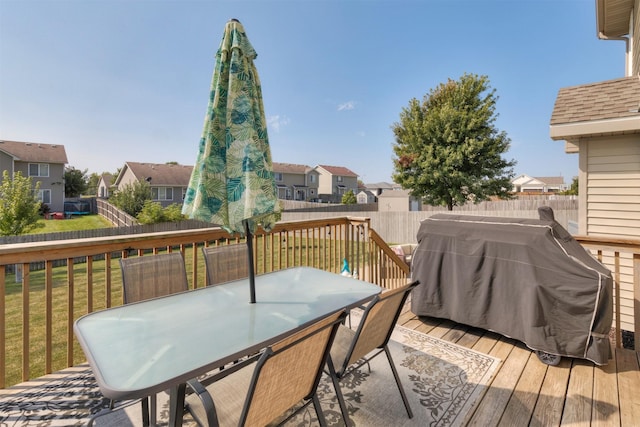 wooden terrace featuring a lawn and a grill