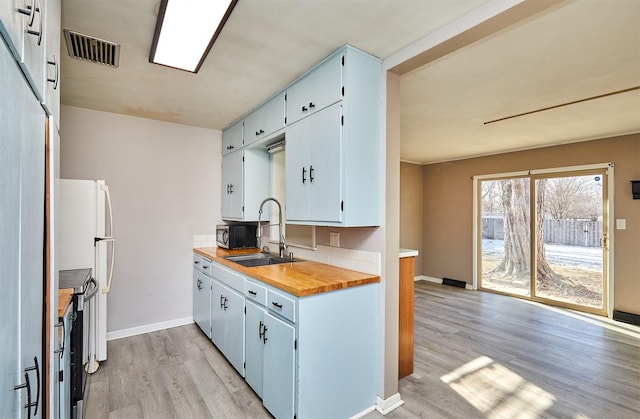 kitchen with wooden counters, sink, light hardwood / wood-style floors, stainless steel electric range oven, and white fridge