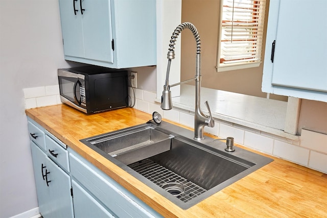 kitchen featuring tasteful backsplash, sink, wooden counters, and blue cabinets