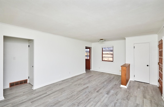 empty room with light wood-type flooring and crown molding