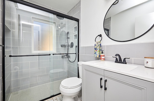 bathroom with walk in shower, vanity, tile walls, and toilet