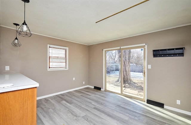 unfurnished dining area featuring crown molding and light hardwood / wood-style flooring