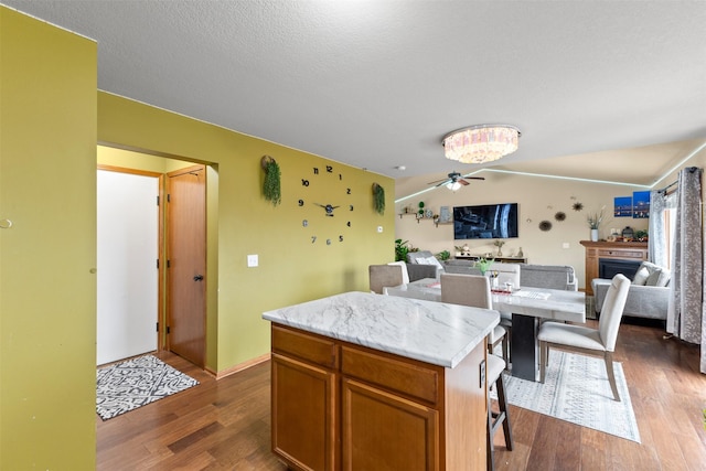 kitchen with a kitchen breakfast bar, vaulted ceiling, ceiling fan, hardwood / wood-style floors, and a kitchen island