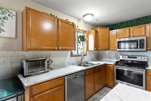 kitchen with decorative backsplash, appliances with stainless steel finishes, a textured ceiling, and sink