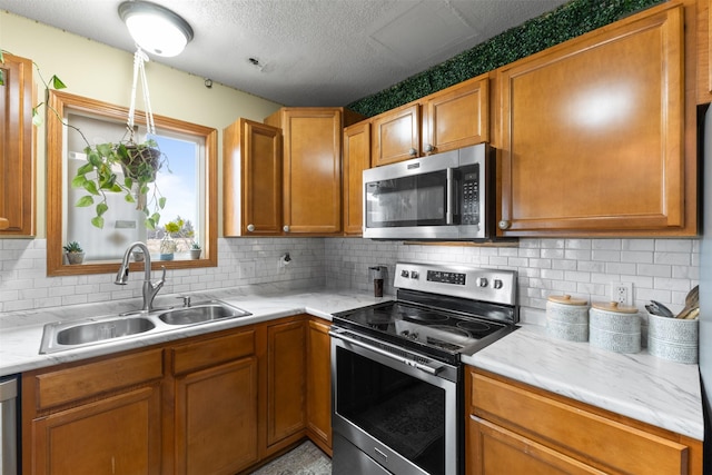 kitchen with backsplash, sink, stainless steel appliances, and a textured ceiling