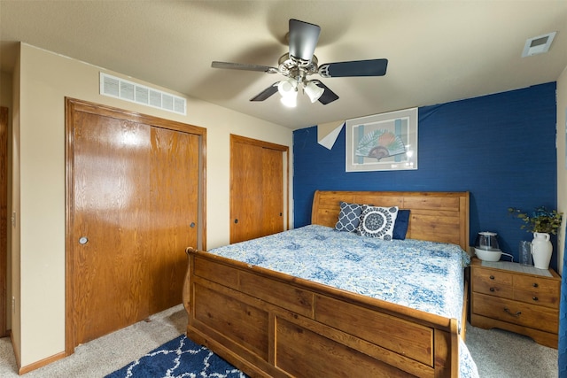 carpeted bedroom with ceiling fan and multiple closets