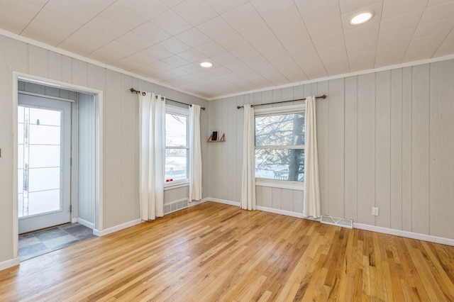 spare room with light wood-type flooring and ornamental molding