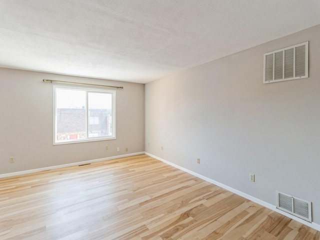 empty room featuring a textured ceiling and light wood-type flooring