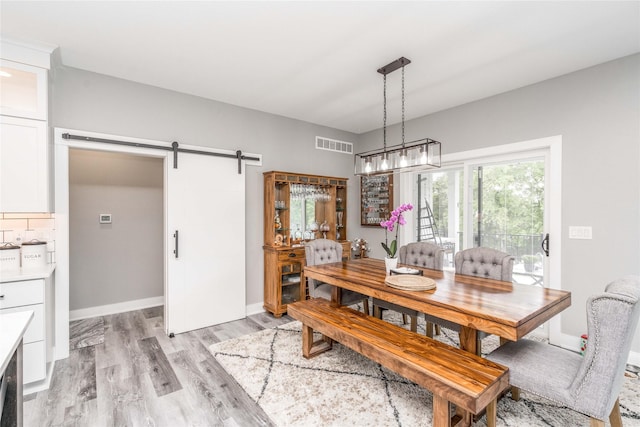 dining area with light wood-type flooring and a barn door