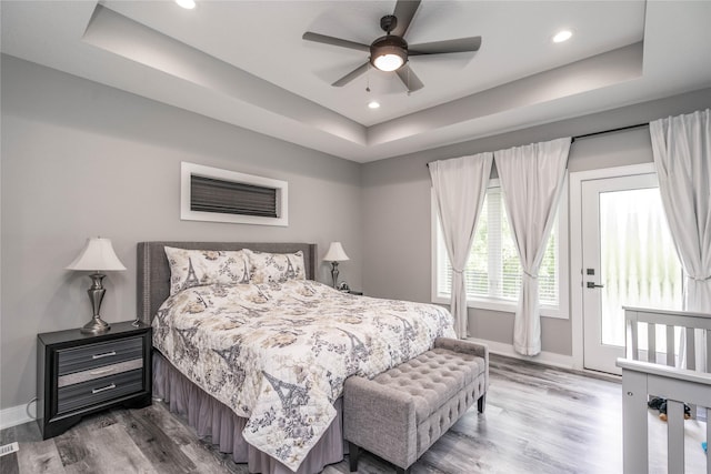 bedroom featuring a tray ceiling, ceiling fan, and wood-type flooring