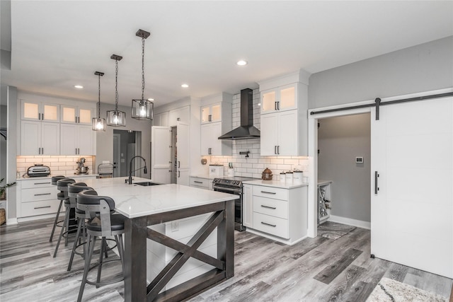 kitchen with electric range, a large island, a barn door, and white cabinets