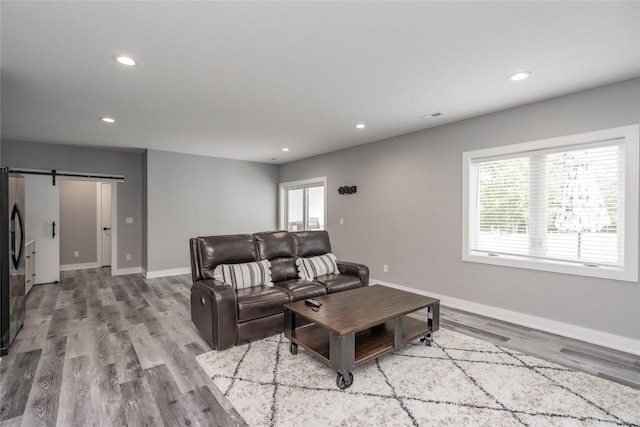 living room with a barn door and light wood-type flooring