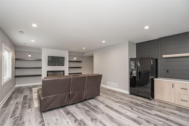 living room with a large fireplace and light hardwood / wood-style flooring