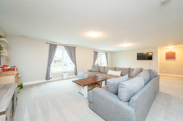 living area with light carpet, baseboards, and a textured ceiling