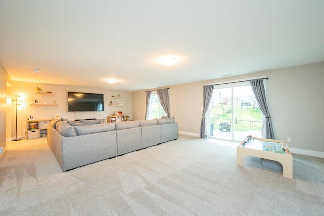 living room featuring light carpet, baseboards, and a wealth of natural light