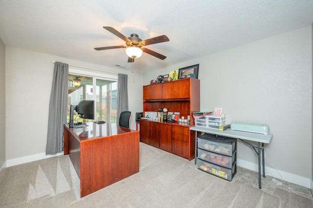 office space with light carpet, ceiling fan, a textured ceiling, and baseboards