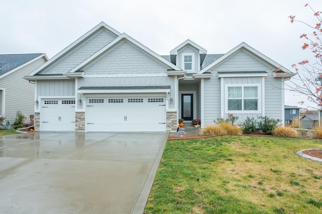 craftsman-style home with driveway, an attached garage, a front lawn, stone siding, and board and batten siding
