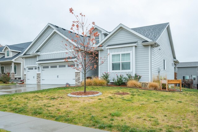 view of front of house featuring a front yard, driveway, a shingled roof, a garage, and board and batten siding