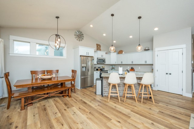 kitchen with stainless steel appliances, light countertops, a kitchen bar, white cabinetry, and pendant lighting