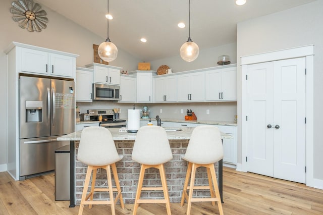 kitchen featuring white cabinets, light stone counters, stainless steel appliances, and pendant lighting