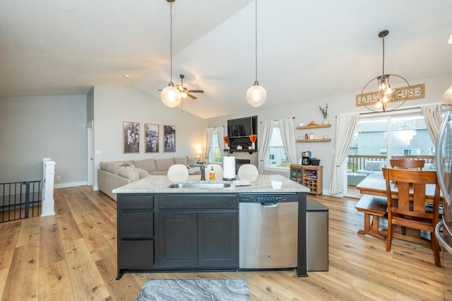 kitchen with stainless steel dishwasher, a sink, decorative light fixtures, and dark cabinets