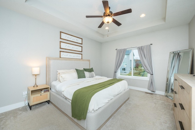 bedroom with recessed lighting, a raised ceiling, light carpet, and baseboards