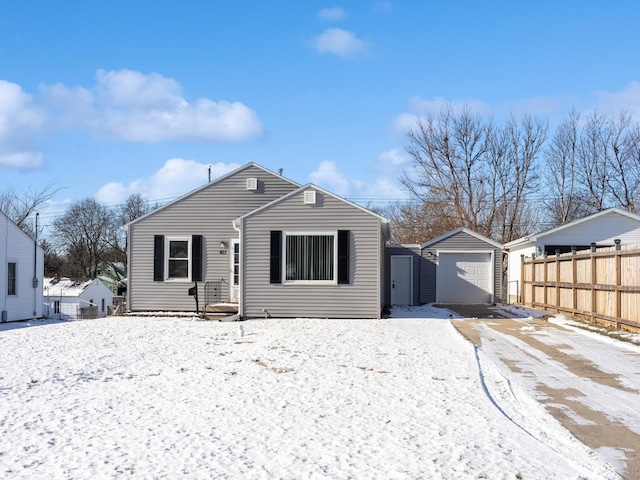 snow covered rear of property with an outbuilding and a garage