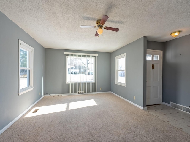 carpeted empty room with ceiling fan and a textured ceiling