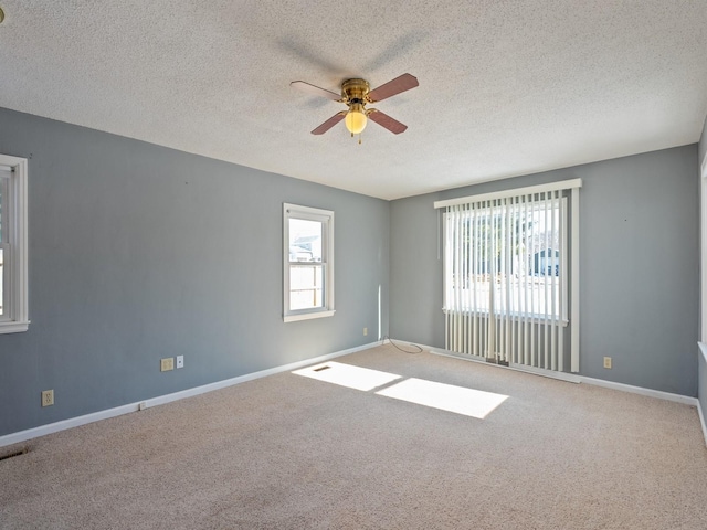 carpeted spare room featuring a textured ceiling, plenty of natural light, and ceiling fan