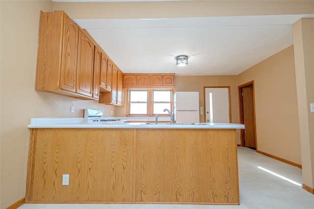 kitchen with white refrigerator, sink, range, and kitchen peninsula