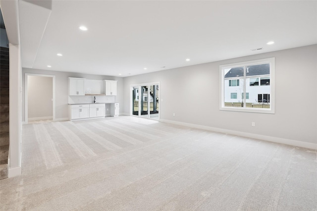 unfurnished living room featuring sink and light carpet