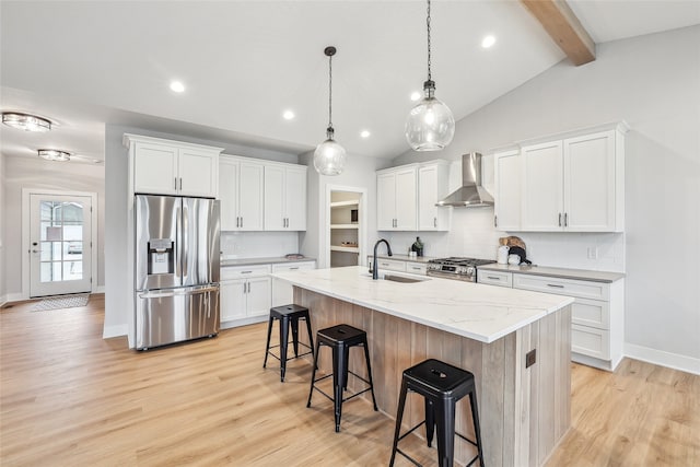 kitchen featuring a kitchen island with sink, wall chimney range hood, sink, white cabinetry, and stainless steel appliances