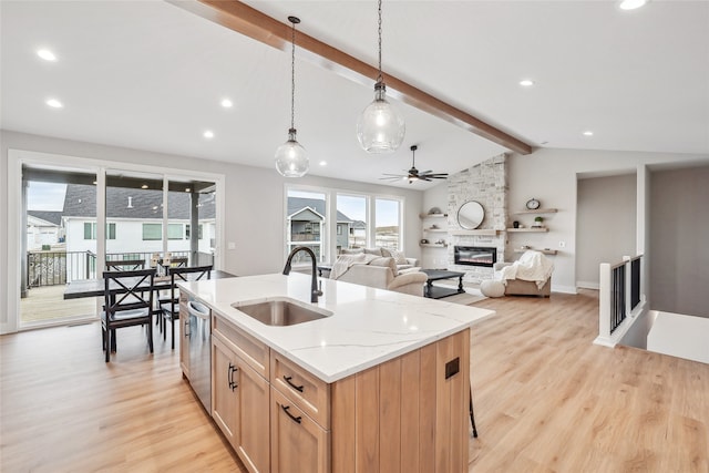 kitchen with lofted ceiling with beams, sink, stainless steel dishwasher, decorative light fixtures, and light stone counters